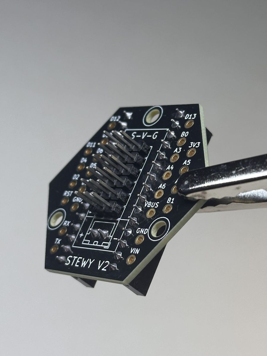 Stewy V2 base circuit board held in tweezers
